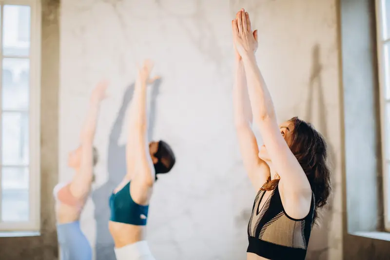 Group of women performing yoga poses indoors, emphasizing mindfulness and wellness
