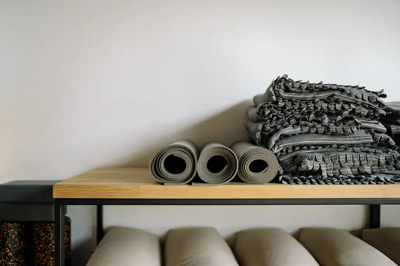 Neatly arranged yoga mats and blankets on a shelf in a serene yoga studio setting