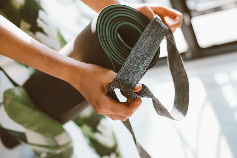 Close-up of a woman's hands holding a yoga mat with a strap. Perfect for fitness and lifestyle concepts