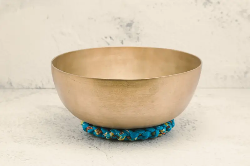 Close-up of a Tibetan singing bowl resting on a vibrant cushion, ideal for meditation practice