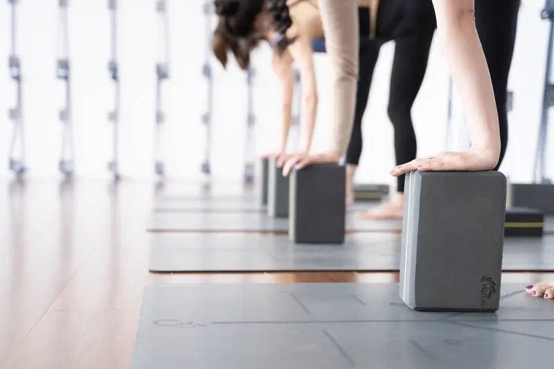 A group of women practicing yoga using blocks in a bright studio setting