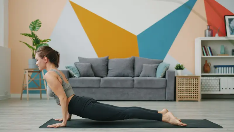 Woman practicing yoga at home in a modern living room with geometric wall art